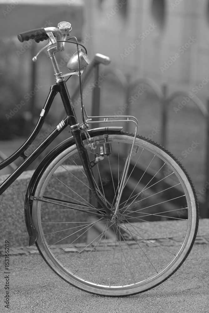 Black bicycle with white wheels on a blurred city background.