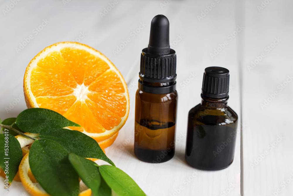 Orange, leaves and brown bottles with essential oil on wooden table Orange, leaves and brown bottles with essential oil on wooden table