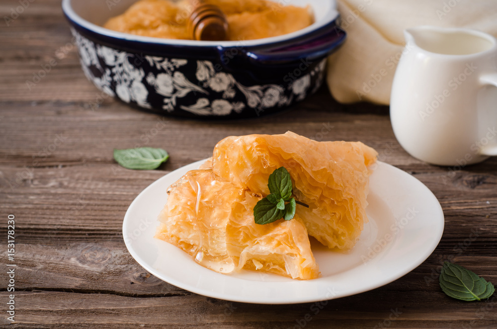 Slice of Homemade baklava stuffed cream with honey sirup on wooden table. Eastern sweets. Ramadan food Slice of Homemade baklava stuffed cream with honey sirup on wooden table. Eastern sweets. Ramadan food
