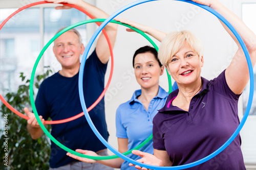 Foto Senior couple in physiotherapy doing exercise with hula hoop