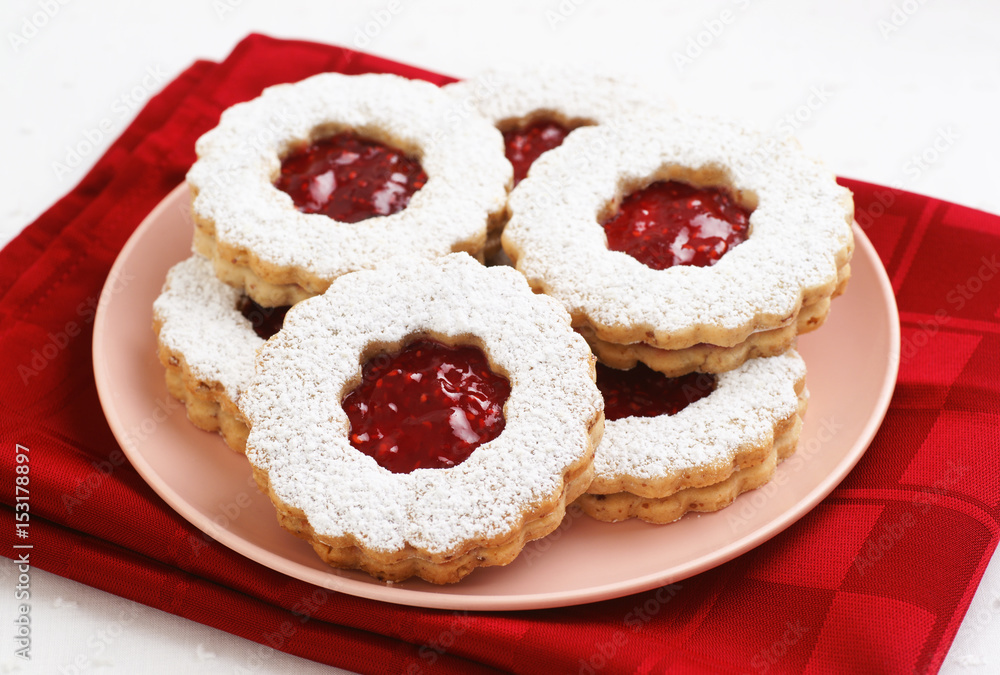 Raspberry Filled Linzer Torte Cookies on Plate and White Background Raspberry Filled Linzer Torte Cookies on Plate and White Background