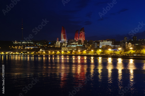 Baku night cityscape with flaming towers and reflections in the Caspian sea bay