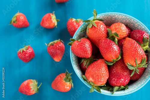 close top view of somefresh strawberries in a bowl isolated on a blue background