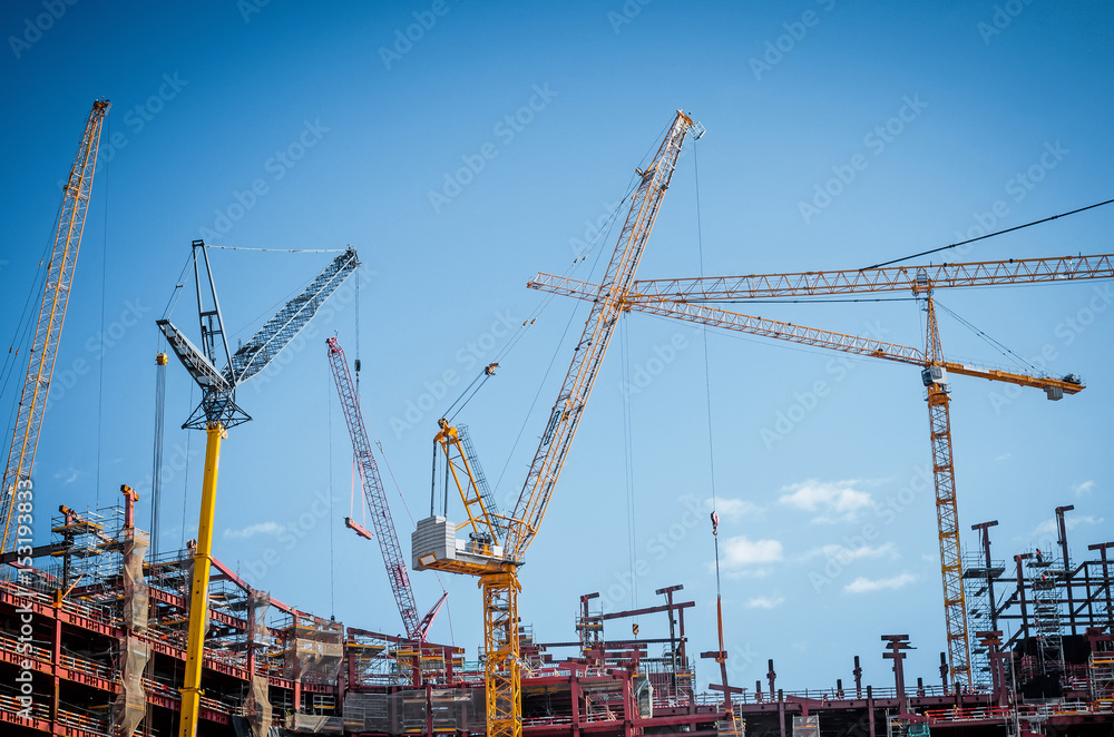Lot of cranes on a large building construction and a blue sky.