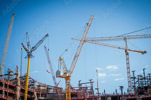 Lot of cranes on a large building construction and a blue sky.