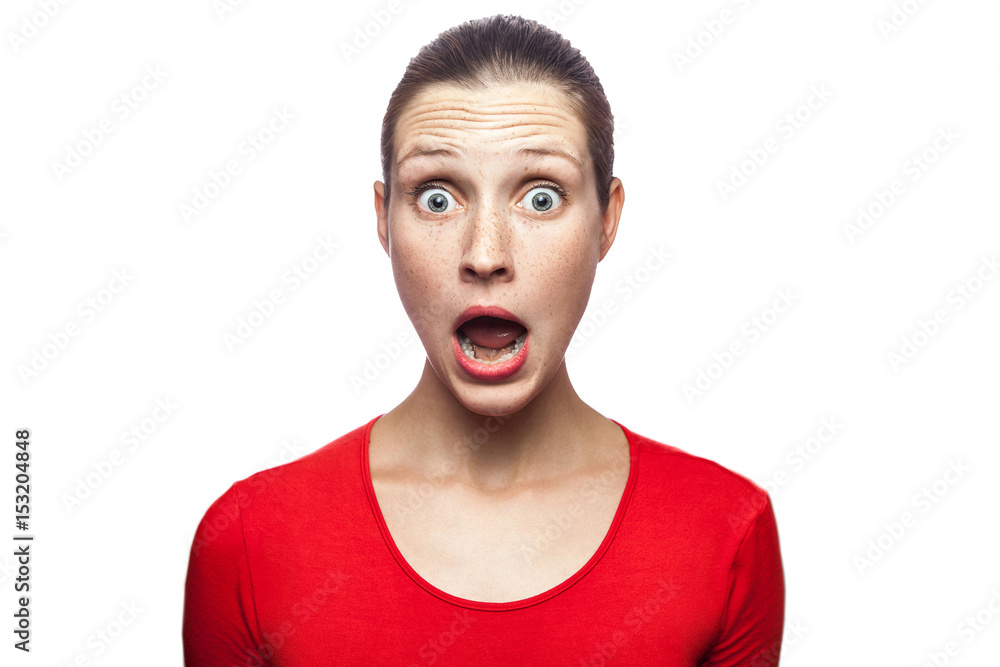 Portrait of happy surprised woman in red t-shirt with freckles. looking at camera excited with big eyes, studio shot. isolated on white background.