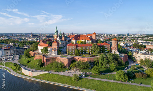 Krakow, Poland. Wawel hill with historic royal castle and cathedral, Vistula River, park and walking people. Aerial view at sunset.