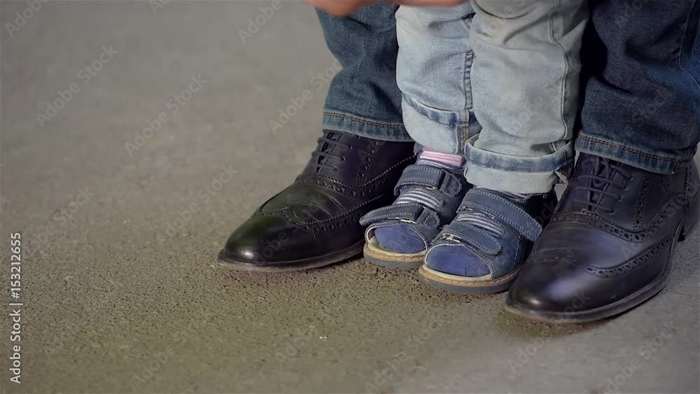 Children's and adult shoes on the asphalt track close-up. Children's and adult shoes on the asphalt track close-up.