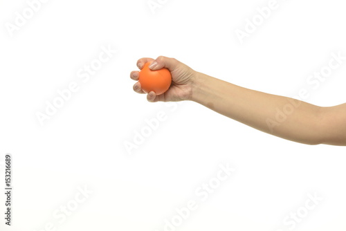 The hand holds an orange round object