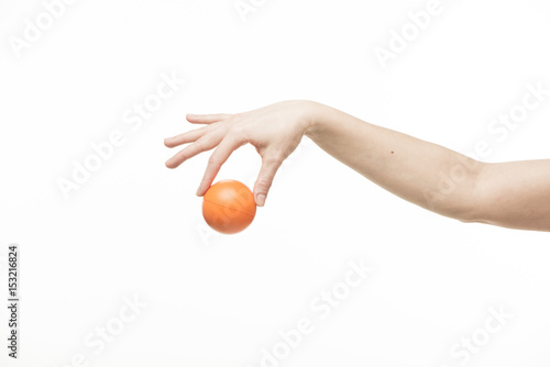 The hand holds an orange round object