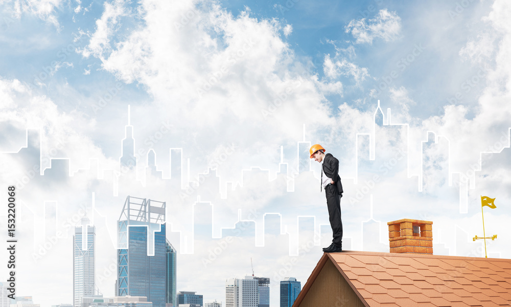 Engineer man standing on roof and looking down. Mixed media Engineer man standing on roof and looking down. Mixed media