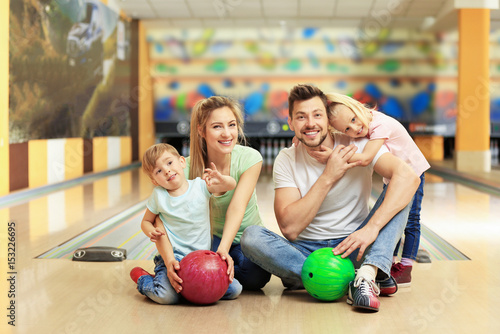 Happy family sitting on floor in bowling club