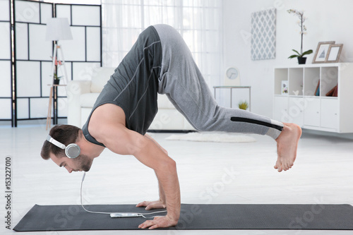 Man doing yoga and listenin...