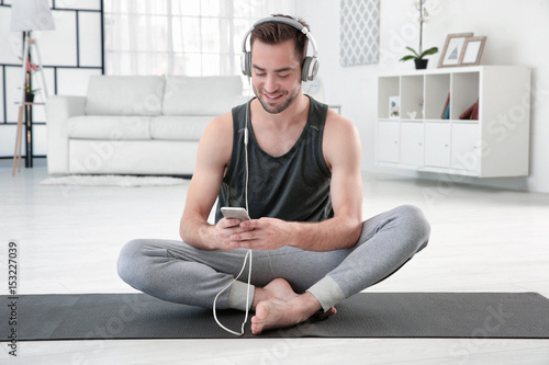 Man doing yoga and listenin...