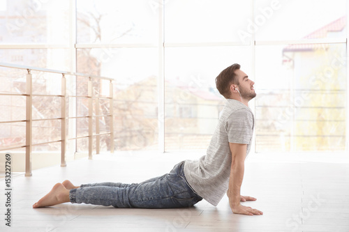 Man doing yoga and listenin...