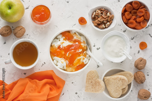 Fototapeta Naklejka Na Ścianę i Meble -  Cottage cheese / Cottage cheese with apricot jam, sour cream, yogurt, dried apricot, apple, walnut and cup tea with biscuits for healthy breakfast