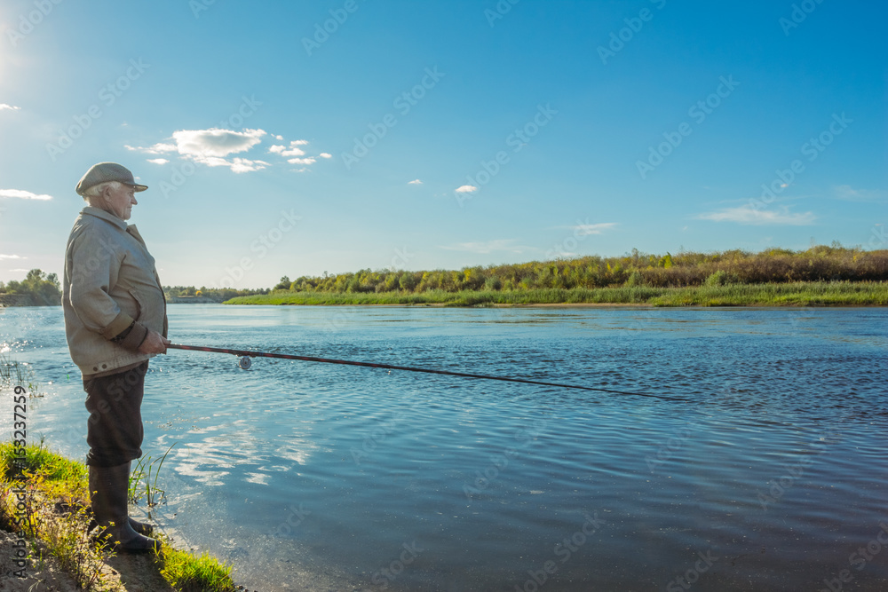 Grandfather on the riverbank catches fish Grandfather on the riverbank catches fish