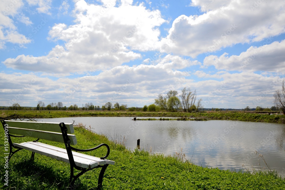 White bench on the shore of the lake and blue sky