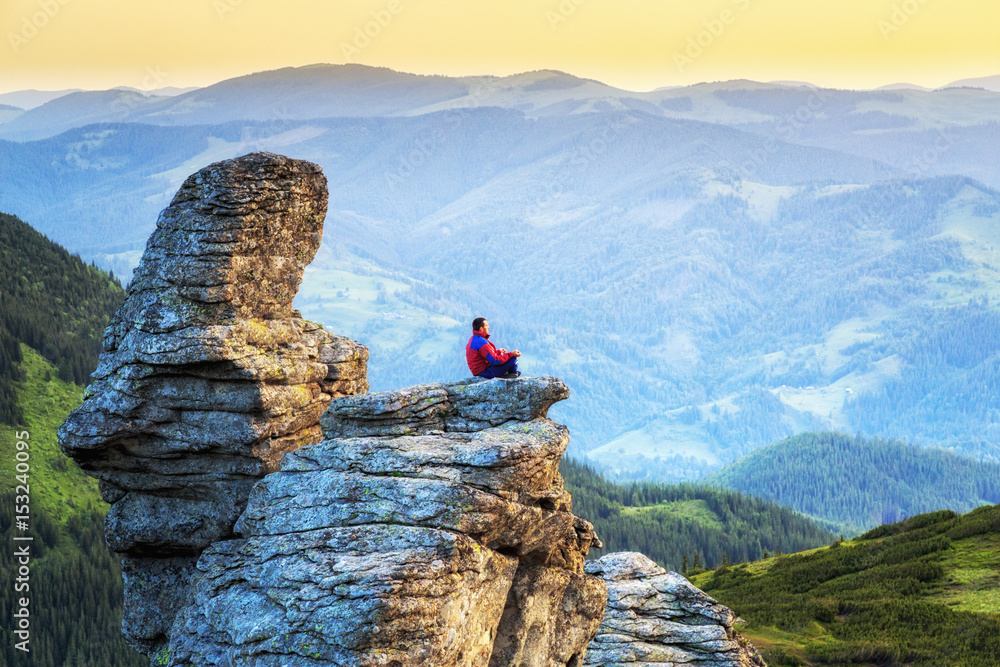 Man meditates in a lotus pose on rock in the mountains. Mountain landscape. Yoga lifestyle.