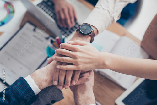 Close up top view cropped photo of hands on top of each other of business partners who are working in successful team for one goal