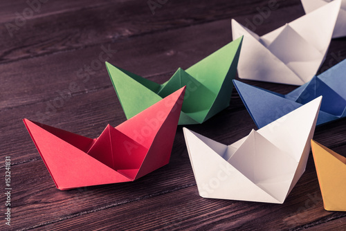 Business leadership concept with white and color paper boats on 