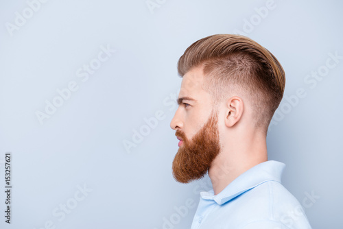 Advertising barbershop concept. Profile side portrait of confident handsome red bearded young man. He has a perfect stunning hairstyle, modern haircut
