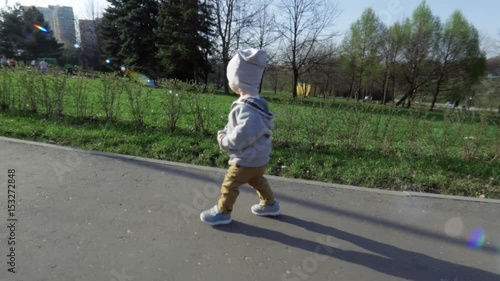 Wallpaper Mural Little cute boy with confident rapid steps walks along the road in the park in summer at sunlight. In the background there are green lawns and trees. Beautiful summer day in the park Torontodigital.ca