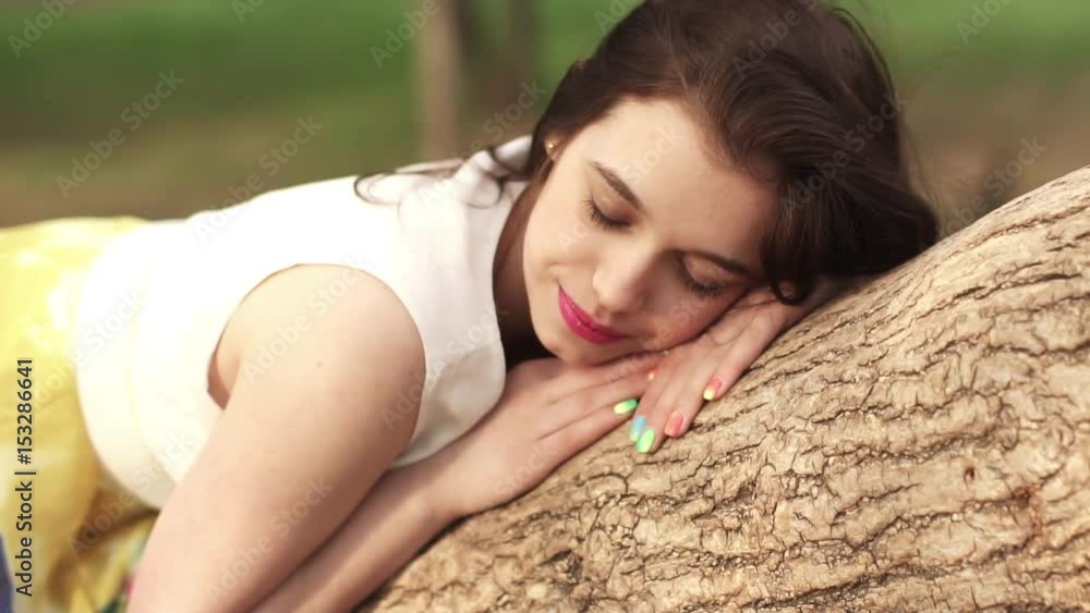 beautiful girl dreaming in the Park lying on a tree branch. beautiful brunette smiling and laughing. slow motion beautiful girl dreaming in the Park lying on a tree branch. beautiful brunette smiling and laughing. slow motion