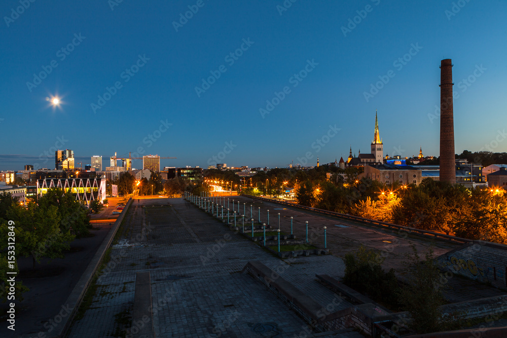 TALLINN, ESTONIA - AUGUST 15, 2016: Aerial cityscape of modern district with tall skyscraper buildings illuminated at night and old town.