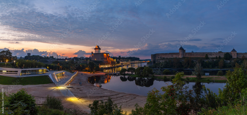 Opposition of two medieval fortresses on the river Narva at sunset, Estonia and Russia border. Wide panoramic view