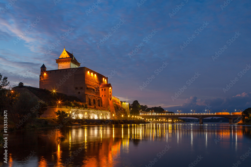 Illuminated medieval fortress on the river Narva, Estonia and Russia border. Blue hour