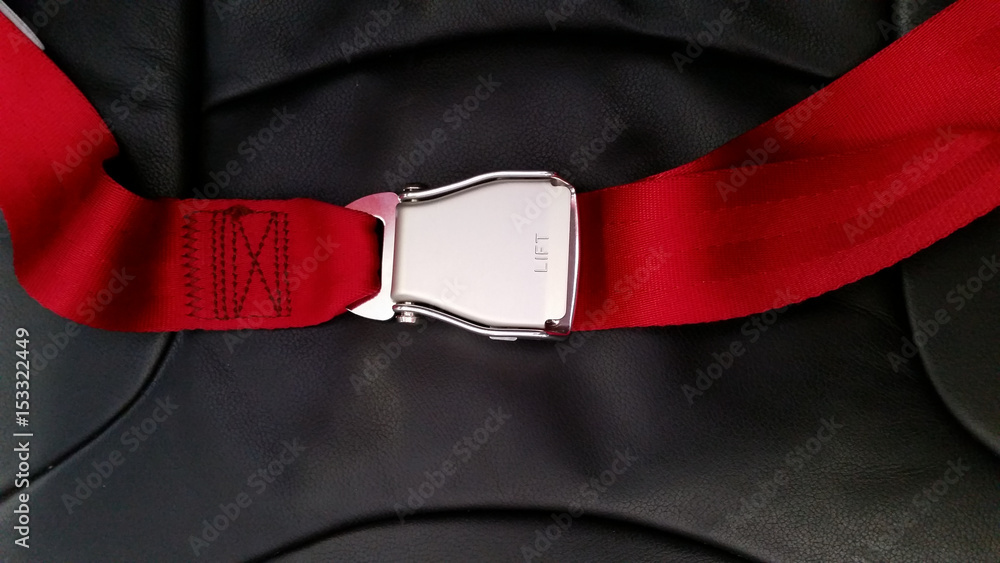 Fototapeta premium Seat belt on seat shot in airplane with Black seat and red carpet.