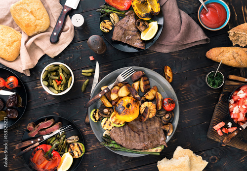 grilled steak and grilled vegetables on dark wooden table