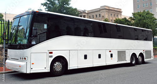 Parked white tour charter bus with dark tinted windows.