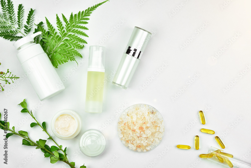 Cosmetic bottle containers with green herbal leaves, Blank label for branding mock-up, Natural beauty product concept.