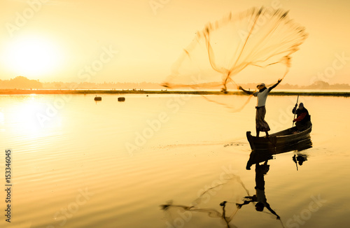 Fisherman throwing fishing net in the morning photo