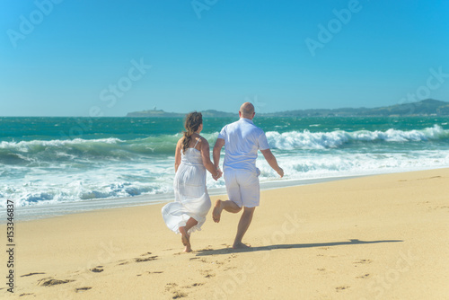 Young romantic couple running on the beach holding hands