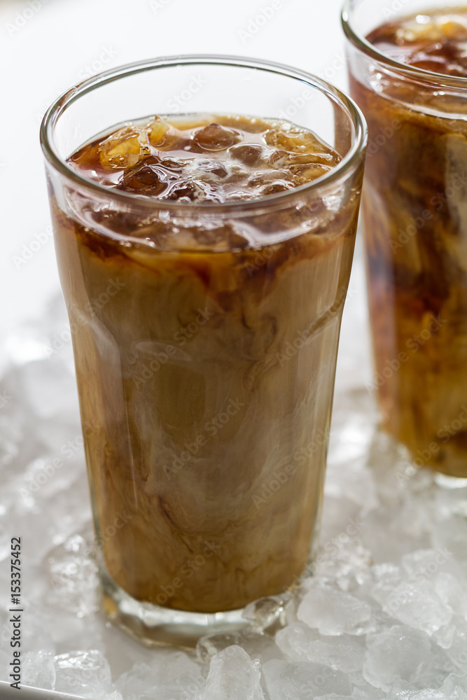 Tasty cold refreshing drink with coffee, milk and ice in glass on ice background. Closeup. Tasty cold refreshing drink with coffee, milk and ice in glass on ice background. Closeup.