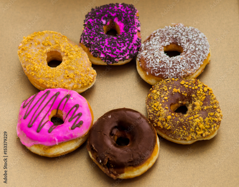 Delicious assorted donuts of different glazed in a soft brown background