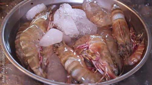 Fresh raw royal tiger prawns in a cup of ice are sold in the local market close-up
