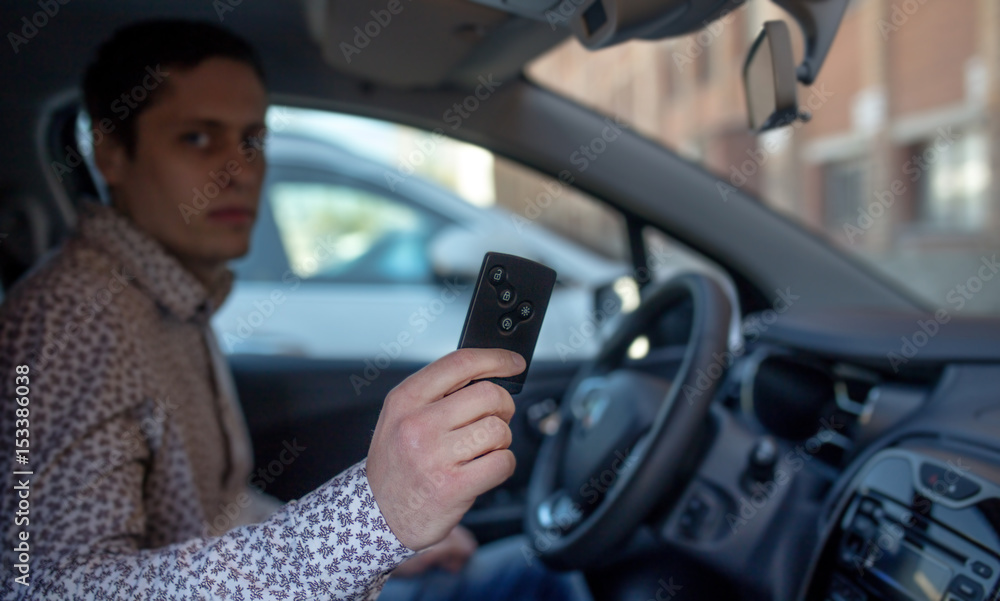 Man looking out from car window and holding a car alarm key. Man blur effect Man looking out from car window and holding a car alarm key. Man blur effect