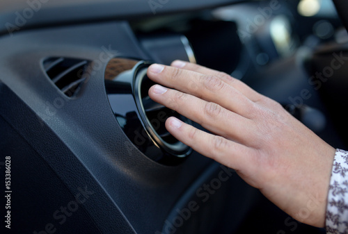 Driver hand on air ventilation grille with power regulator, modern car interior detail