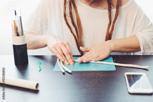 Woman's hands mold out of clay on wooden table