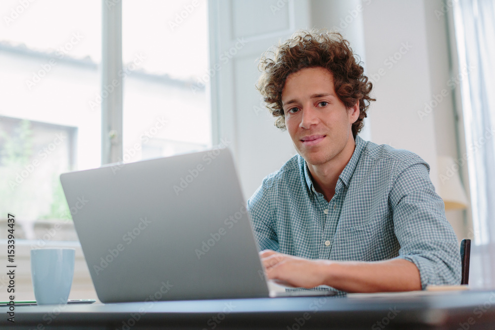 Happy young man working with computer from home Happy young man working with computer from home