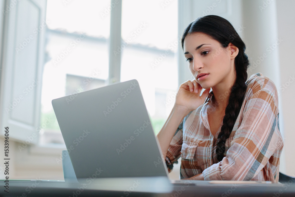 Woman working on laptop computer at home desk Woman working on laptop computer at home desk