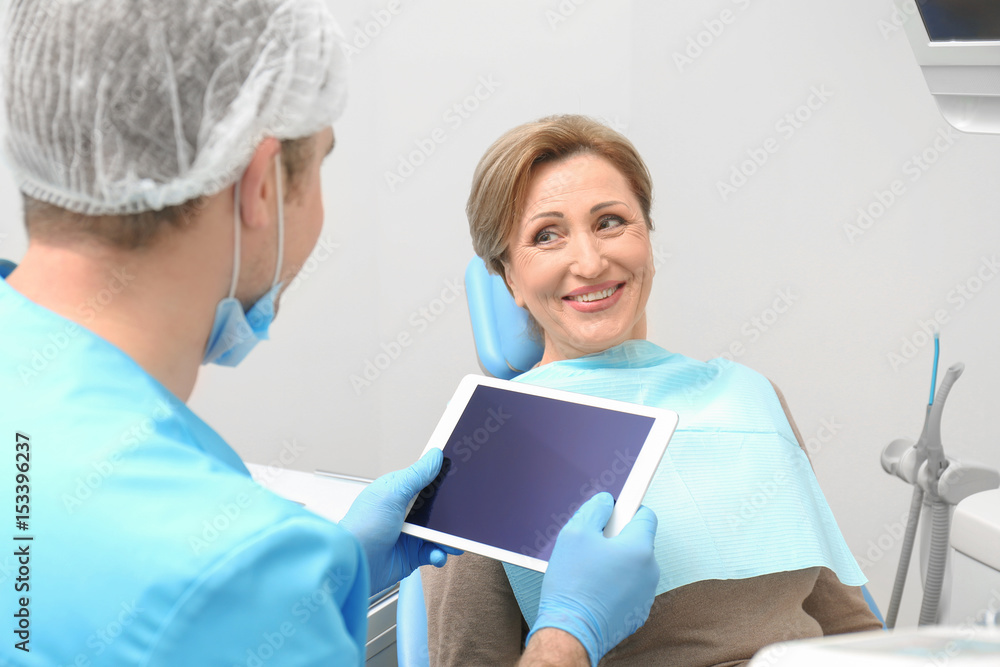Dentist with tablet and female patient in clinic Dentist with tablet and female patient in clinic