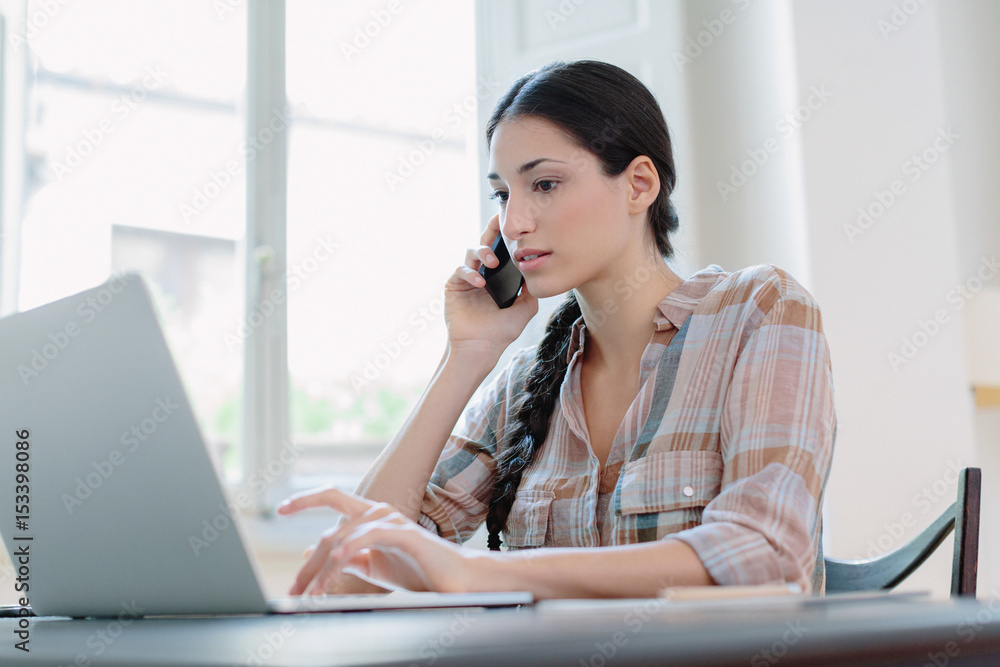 Woman speaking on phone while working with laptop Woman speaking on phone while working with laptop