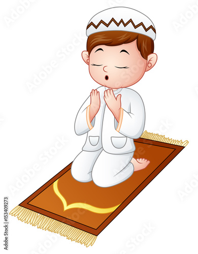Muslim kid sitting on the prayer rug while praying