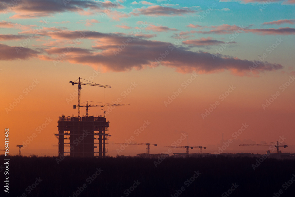 Fototapeta premium Silhouette of building cranes at sunrise
