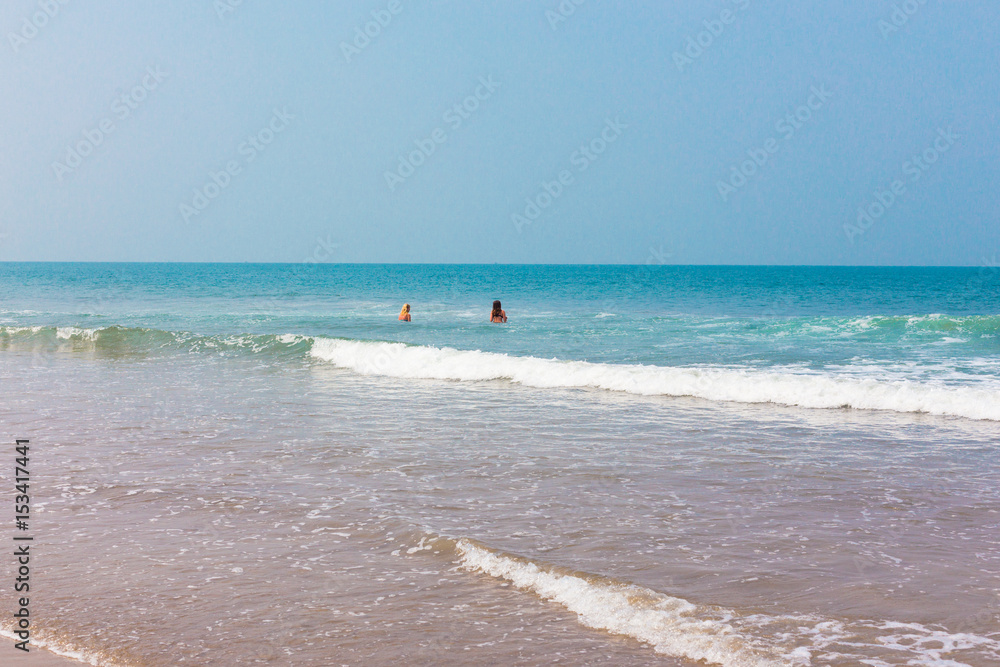 View of the sea from a tropical beach. Two girls are swimming in the ocean. View of the sea from a tropical beach. Two girls are swimming in the ocean.